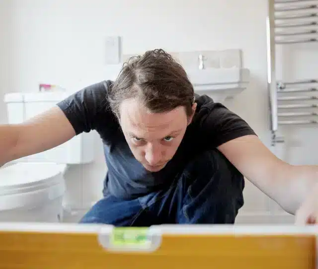 man using level in a tiled bathroom | Pacific Bay Construction man using level in a tiled bathroom | Pacific Bay Construction